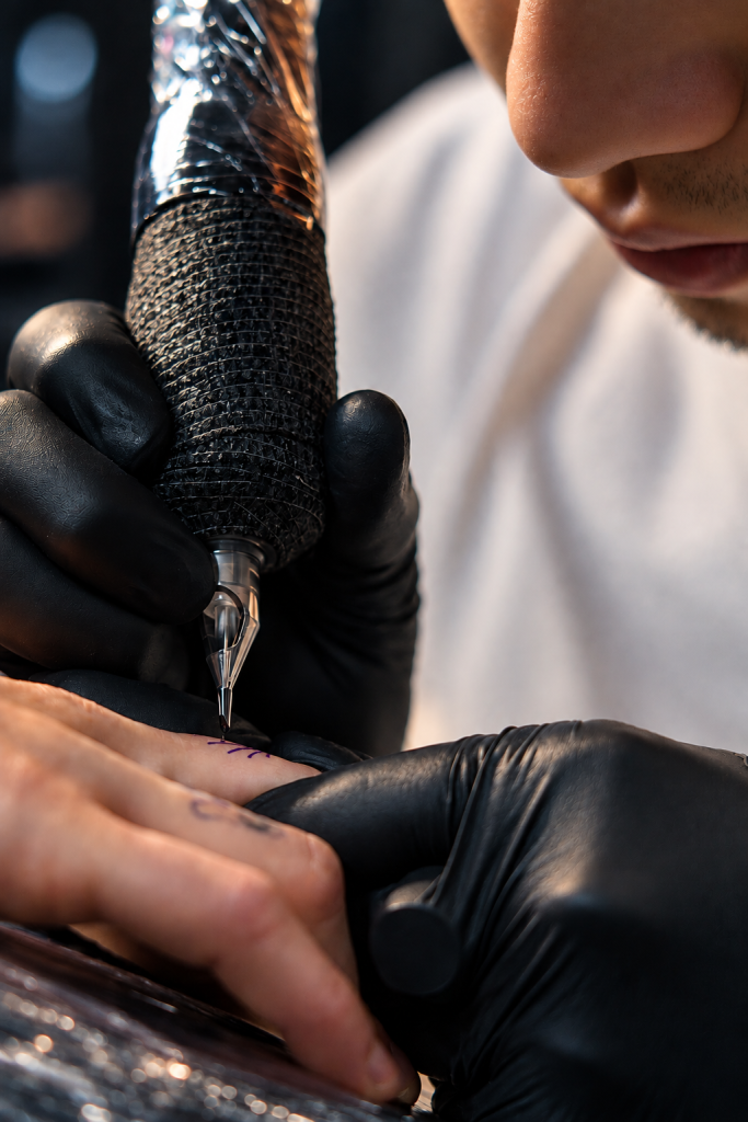 Primer plano de un tatuador trabajando con máquina y guantes negros
